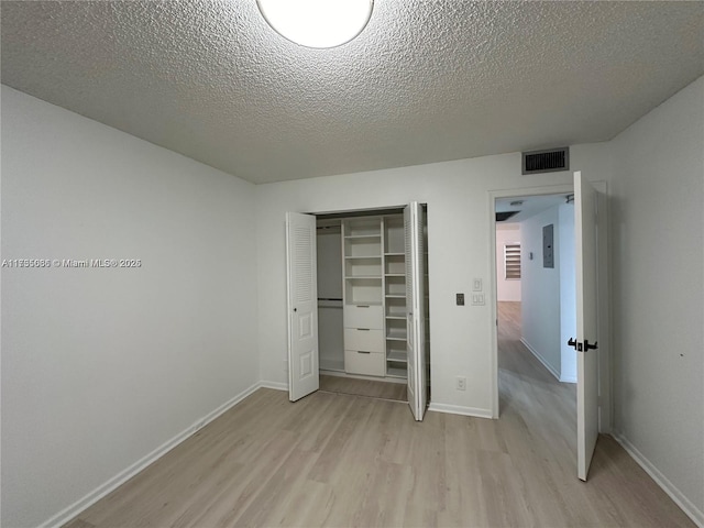 unfurnished bedroom with a closet, a textured ceiling, and light hardwood / wood-style flooring