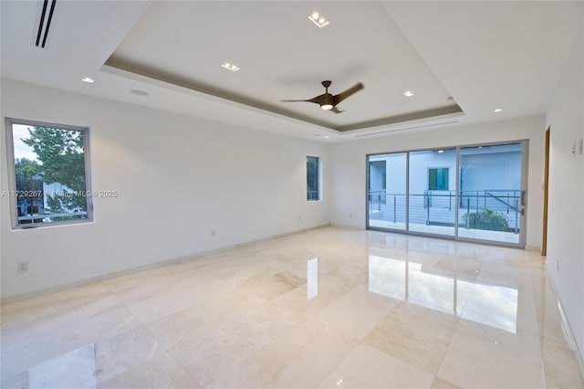 empty room featuring a tray ceiling and ceiling fan