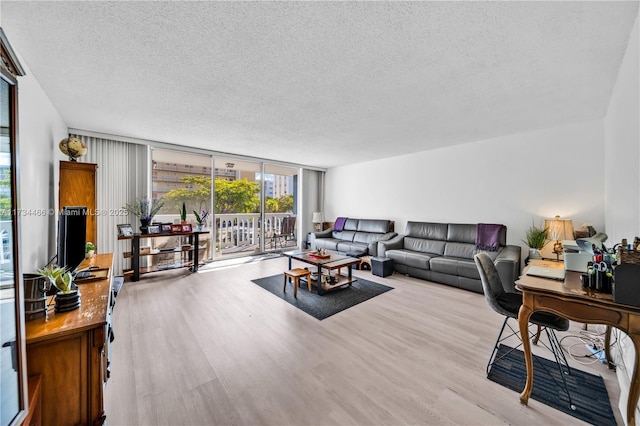 living area with a textured ceiling, a wall of windows, and wood finished floors