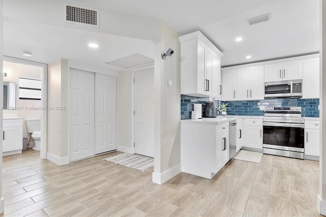 kitchen featuring white cabinetry, appliances with stainless steel finishes, and decorative backsplash