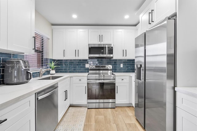 kitchen with tasteful backsplash, sink, white cabinets, stainless steel appliances, and light stone countertops