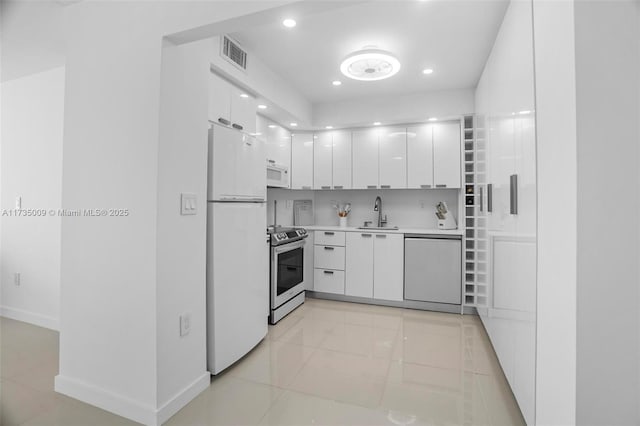 kitchen with sink, white appliances, white cabinets, and light tile patterned flooring