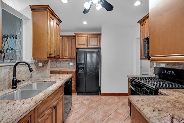 kitchen featuring light stone counters, backsplash, sink, and black appliances