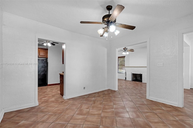 tiled empty room with a textured ceiling and a fireplace