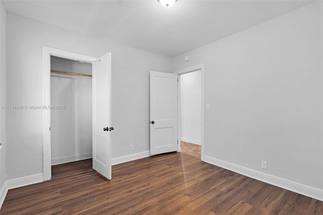 unfurnished bedroom with dark hardwood / wood-style floors and a closet