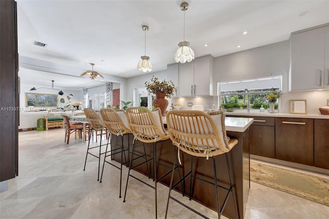 kitchen with white cabinetry, sink, a wealth of natural light, and a kitchen bar