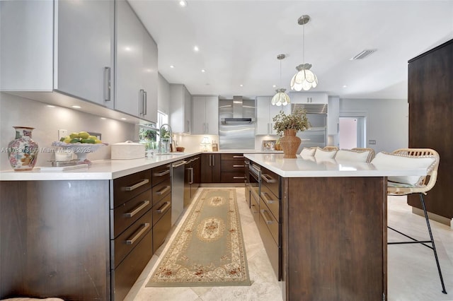 kitchen featuring a breakfast bar, a center island, stainless steel dishwasher, pendant lighting, and wall chimney range hood