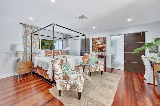 bedroom with hardwood / wood-style flooring and a barn door