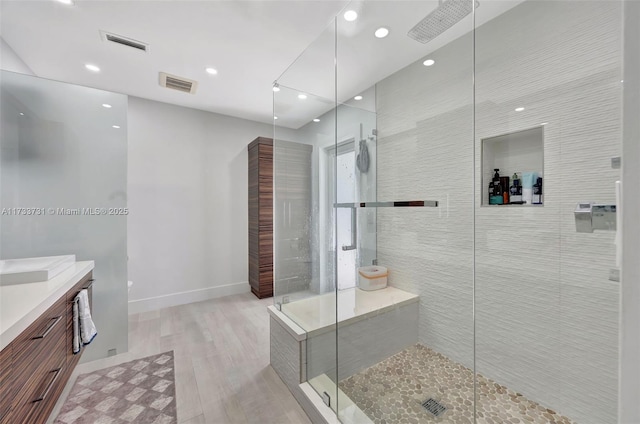 bathroom with vanity, hardwood / wood-style floors, and a tile shower