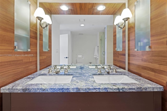 bathroom with vanity, a shower with shower door, and wooden walls