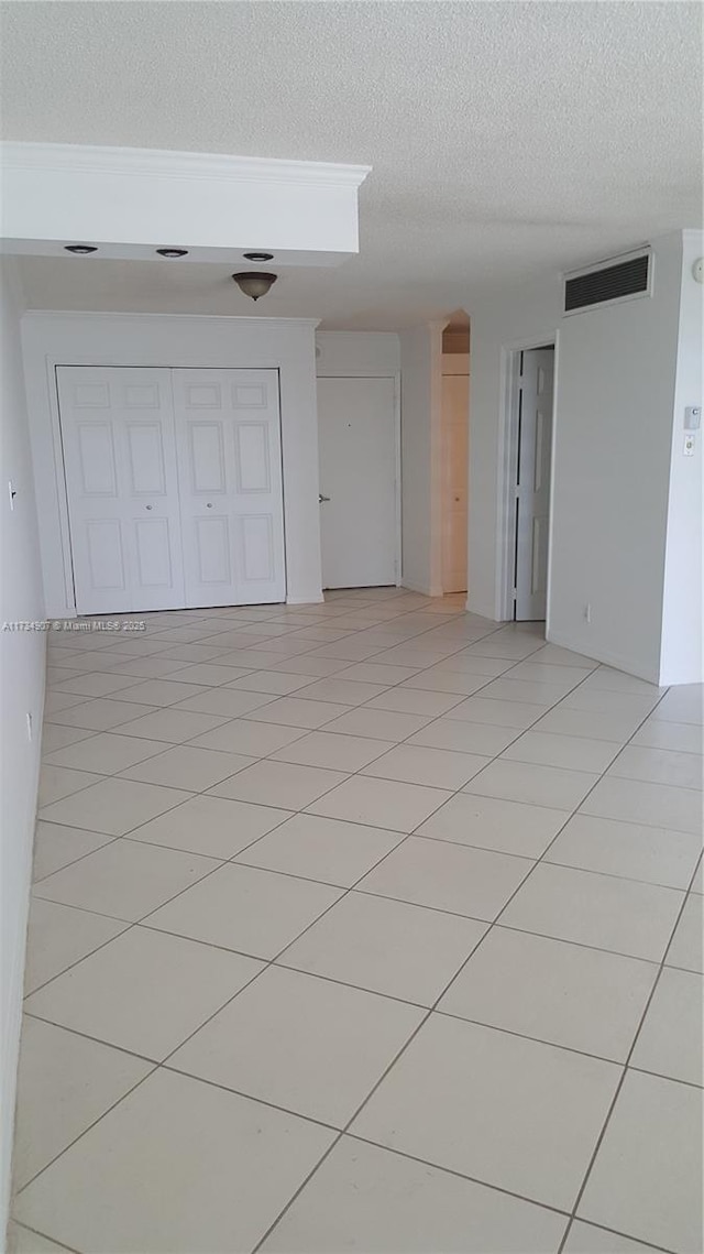 empty room featuring a textured ceiling and light tile patterned floors