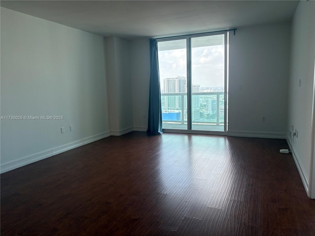 unfurnished room featuring dark wood-type flooring and a wall of windows