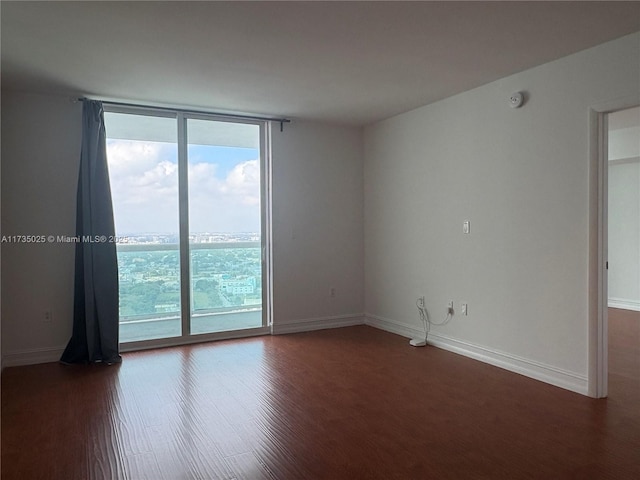 empty room with dark hardwood / wood-style floors and expansive windows