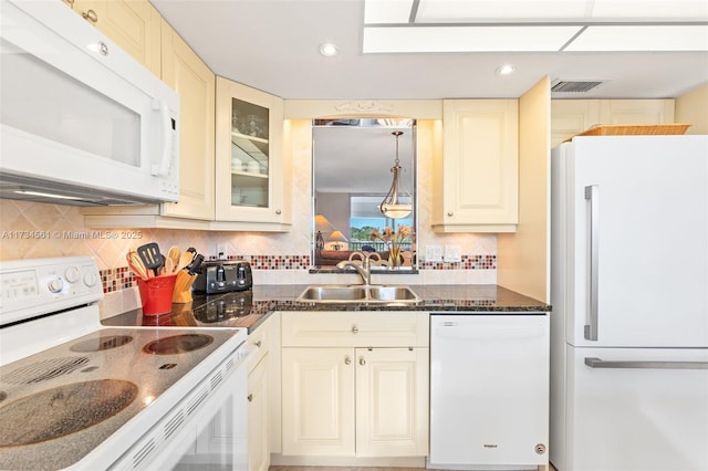 kitchen with sink, dark stone countertops, decorative backsplash, cream cabinets, and white appliances