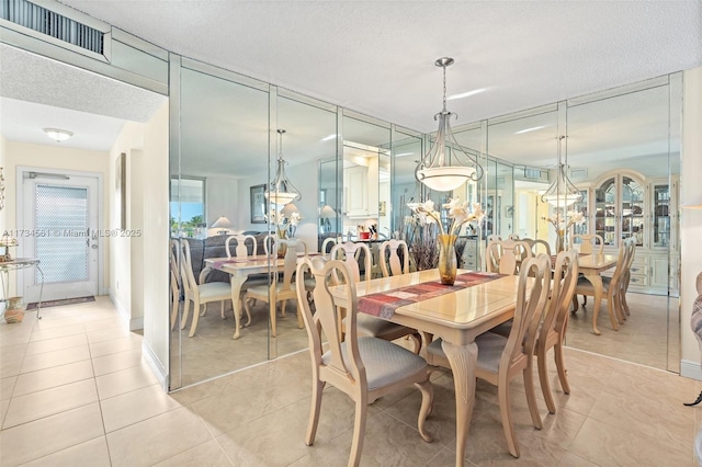 tiled dining space with a notable chandelier and a textured ceiling