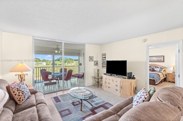 living room with expansive windows, ceiling fan, light tile patterned floors, and a textured ceiling