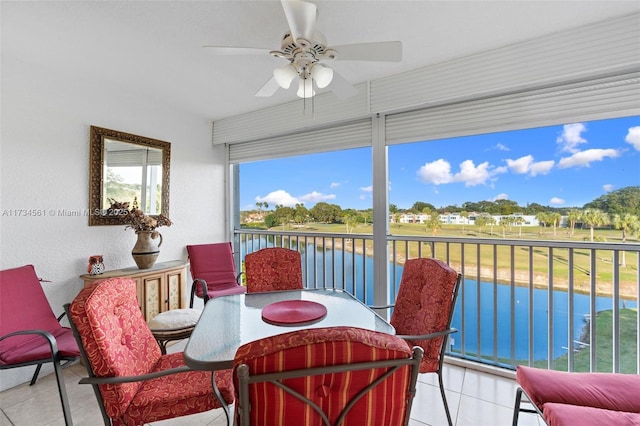 sunroom featuring ceiling fan and a water view