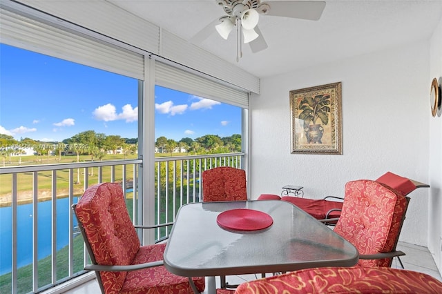 sunroom / solarium featuring a water view and ceiling fan