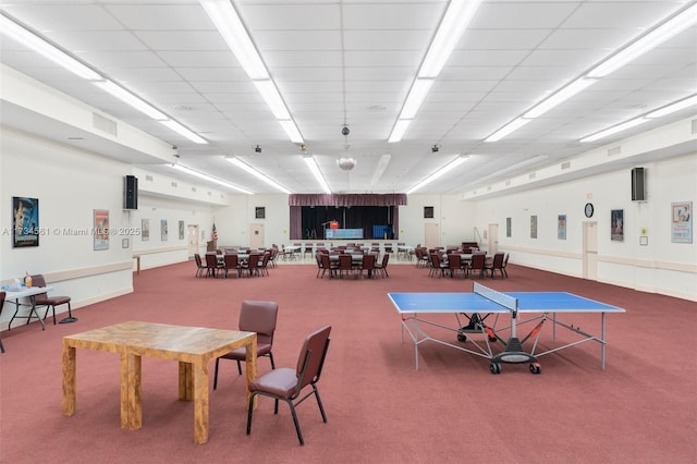 recreation room with carpet floors and a paneled ceiling