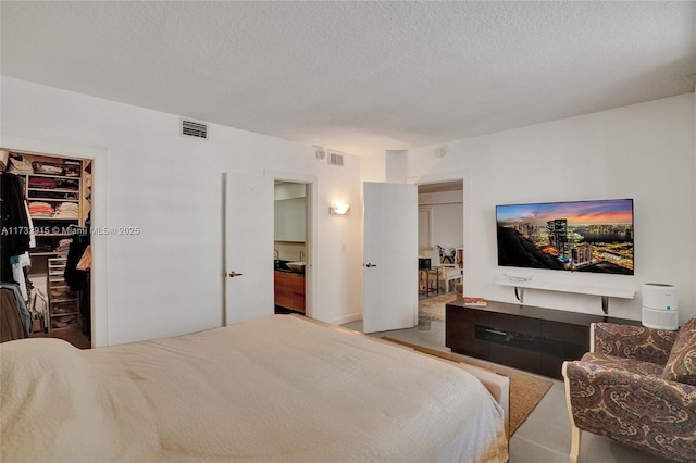 bedroom featuring a walk in closet, a closet, and a textured ceiling