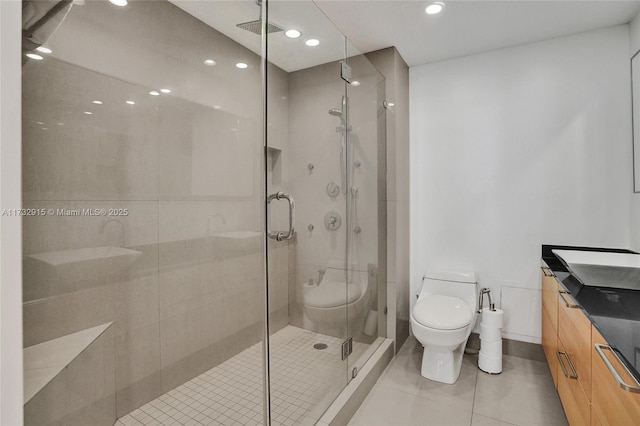 bathroom featuring tile patterned floors, vanity, toilet, and a shower with shower door