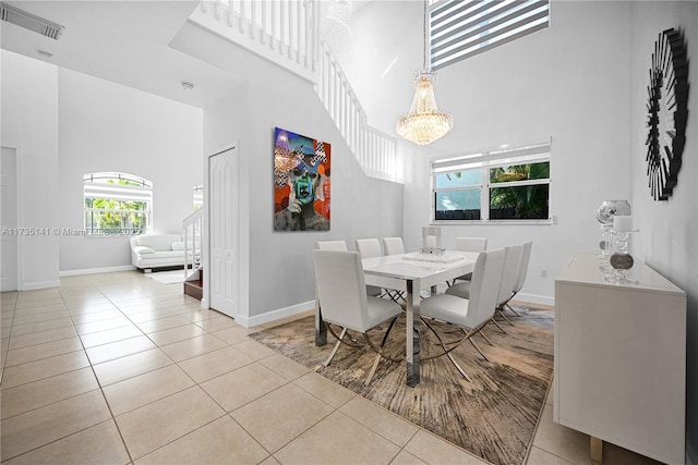 dining room featuring light tile patterned flooring, a towering ceiling, and a chandelier