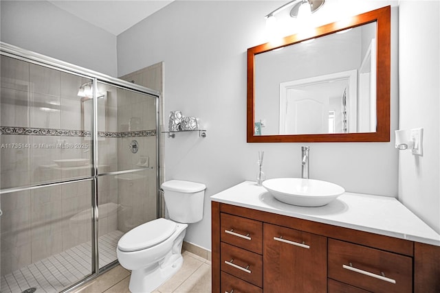 bathroom with vanity, a shower with shower door, tile patterned floors, and toilet