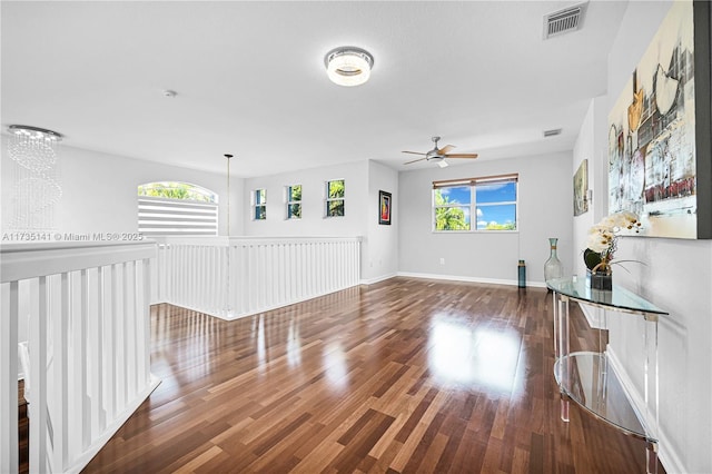 unfurnished living room with ceiling fan with notable chandelier and dark hardwood / wood-style floors