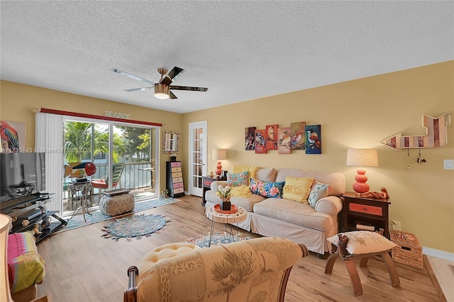 living room featuring a textured ceiling, light hardwood / wood-style floors, and ceiling fan