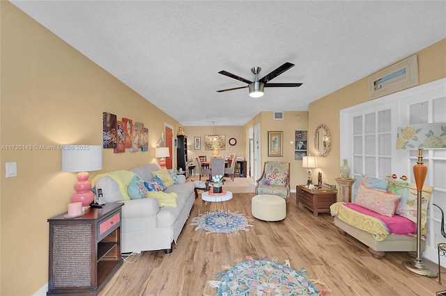 living room featuring ceiling fan, light hardwood / wood-style floors, and a textured ceiling