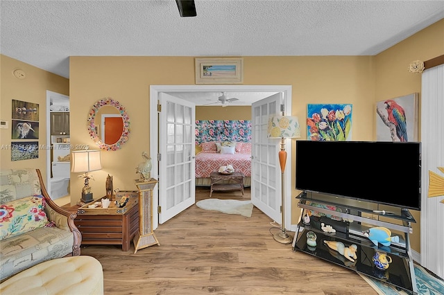 living room featuring hardwood / wood-style flooring, ceiling fan, a textured ceiling, and french doors