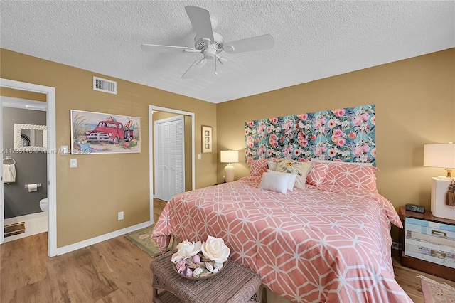 bedroom with hardwood / wood-style flooring, ceiling fan, a textured ceiling, ensuite bath, and a closet