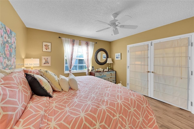 bedroom featuring ceiling fan, light hardwood / wood-style flooring, and a textured ceiling