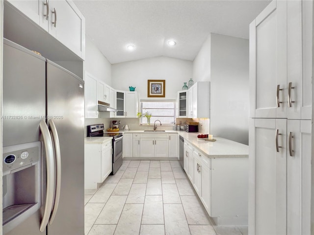 kitchen featuring sink, appliances with stainless steel finishes, a textured ceiling, white cabinets, and vaulted ceiling