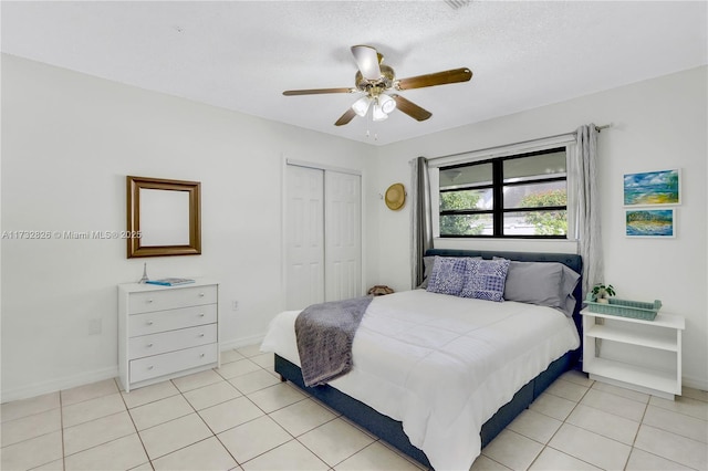 bedroom featuring light tile patterned floors, a textured ceiling, a closet, and ceiling fan