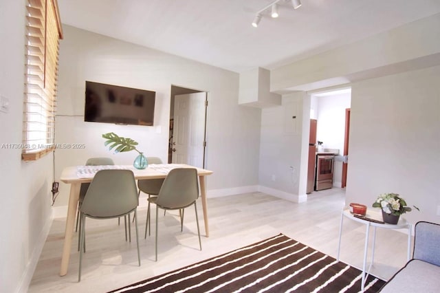 dining space featuring rail lighting and light wood-type flooring