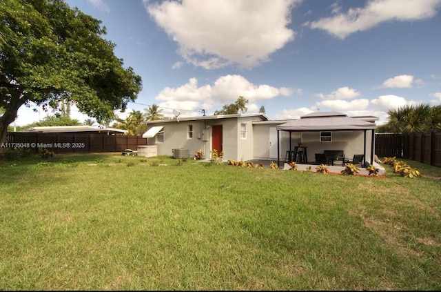 rear view of house with a gazebo, a lawn, central AC unit, and a patio