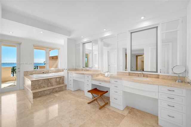 bathroom featuring tiled tub and vanity