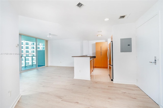 unfurnished room with floor to ceiling windows, electric panel, and light wood-type flooring