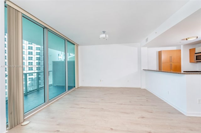 unfurnished room with floor to ceiling windows and light wood-type flooring