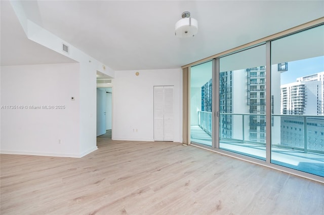 spare room with plenty of natural light, light hardwood / wood-style floors, and floor to ceiling windows