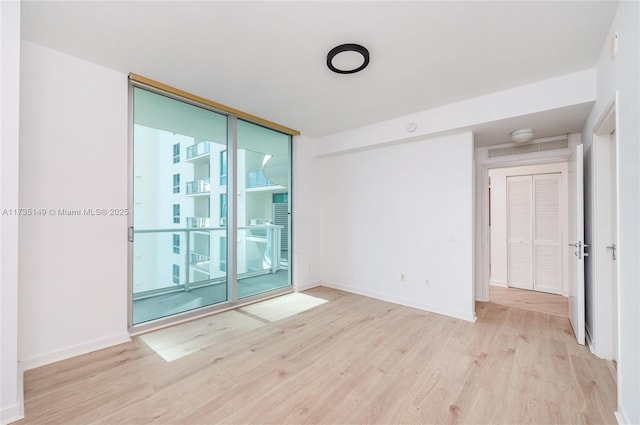 empty room with light hardwood / wood-style flooring and floor to ceiling windows