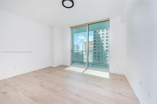 spare room with light hardwood / wood-style floors and expansive windows