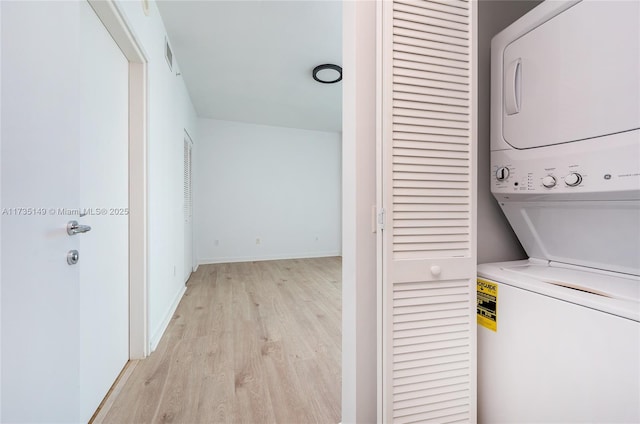 laundry area with stacked washer and dryer and light hardwood / wood-style flooring