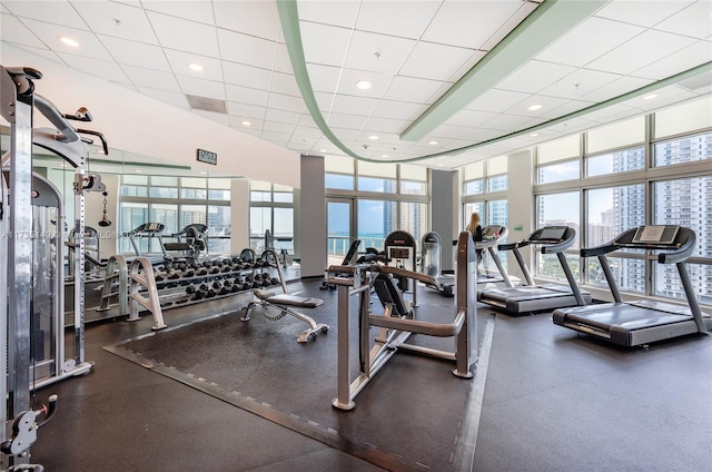 gym with a paneled ceiling and expansive windows