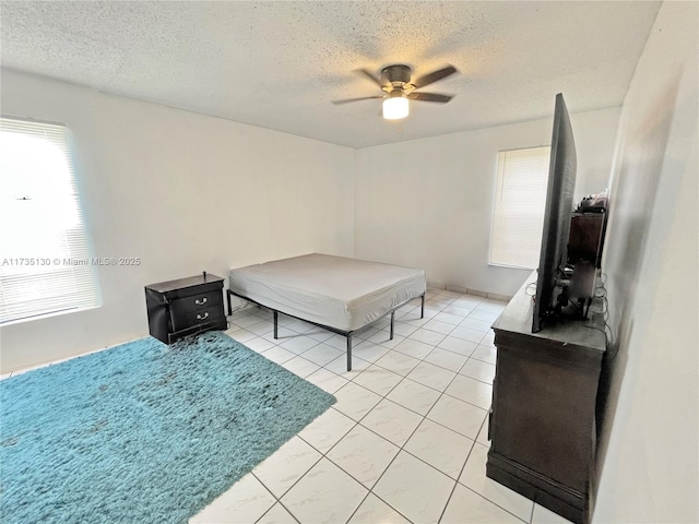 bedroom with light tile patterned flooring, ceiling fan, and a textured ceiling