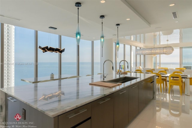 kitchen with a large island, sink, light stone counters, and a water view