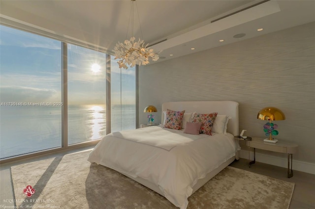 bedroom with a water view, access to outside, a chandelier, and a wall of windows