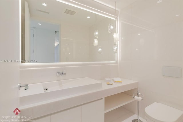 bathroom featuring vanity, tile walls, and toilet