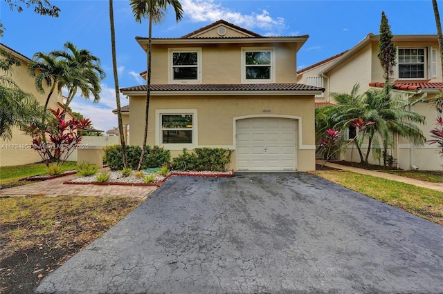 mediterranean / spanish house featuring a garage, stucco siding, a tile roof, and aphalt driveway